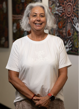 A portrait image of Sharon Gray, a woman smiling wearing a white tshirt