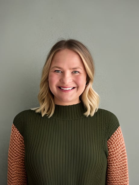 A portrait photo of Nicola Adams, smiling wearing wearing an olive green sweater.